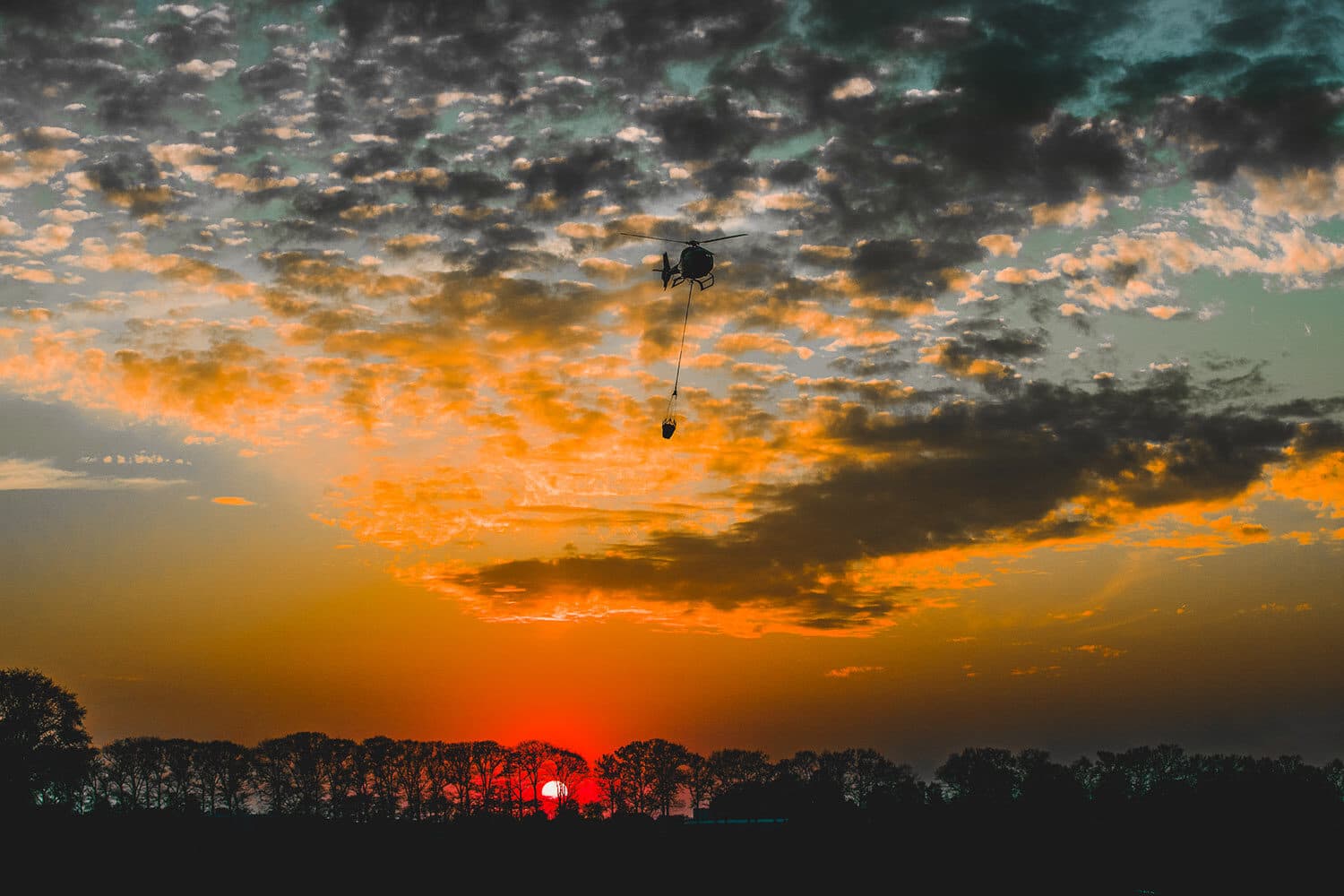 Helikopter met bambi bucket, gefotografeerd vanuit de lucht