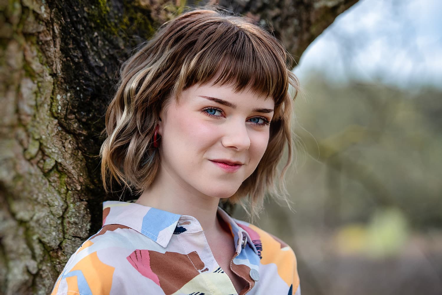 Ontspannen portret van een jonge vrouw tegen een oude boom tijdens een fotoshoot in Otterlo