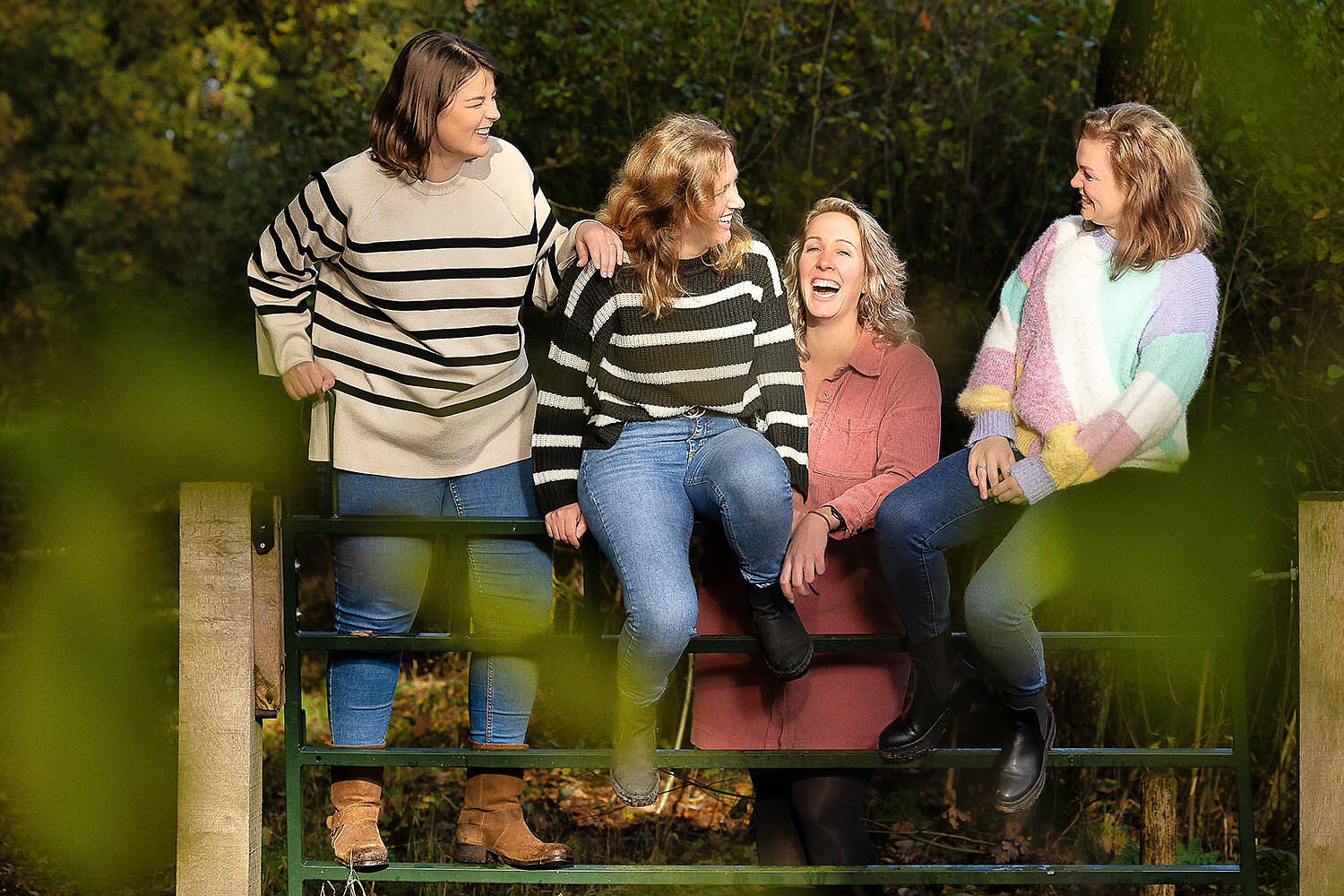 Lachende vriendinnen op een hek tijdens een fotoshoot op het Wekeromse Zand