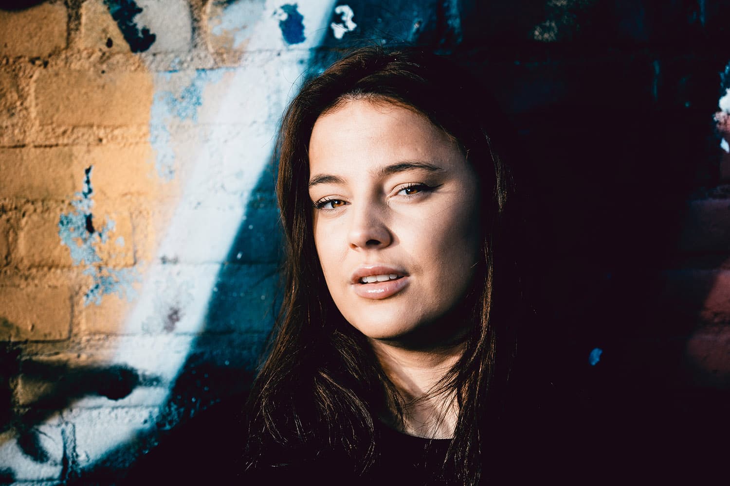 Portret van een jonge vrouw voor een muur met graffiti